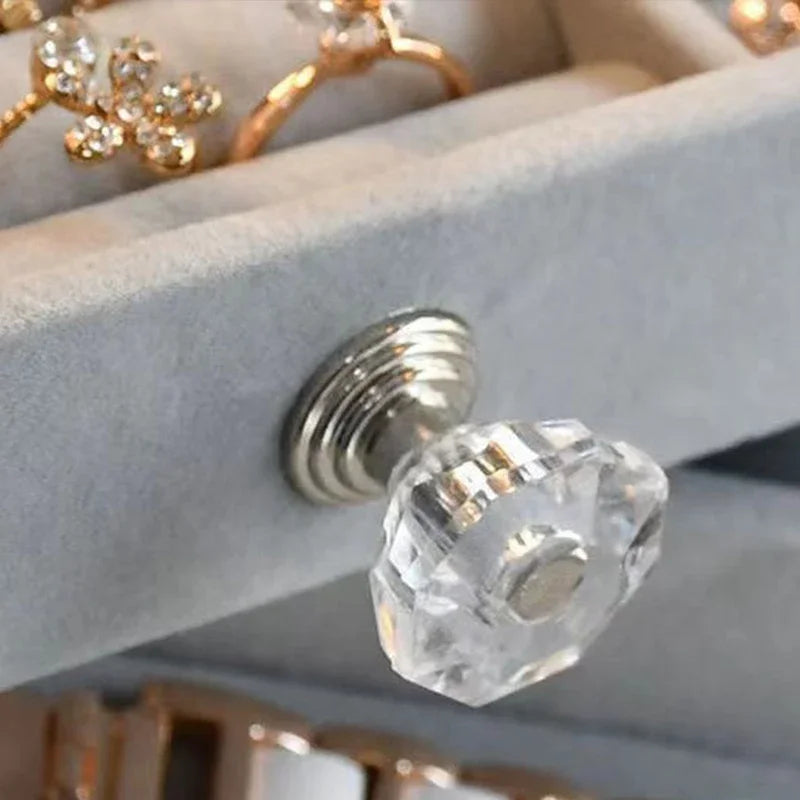 A clear acrylic jewelry organizer featuring multiple compartments and drawers, designed to neatly store and display rings, necklaces, bracelets, and earrings. Its transparent design allows for easy visibility of contents, while the compact structure fits seamlessly on a vanity or dresser, keeping accessories organized and easily accessible.
