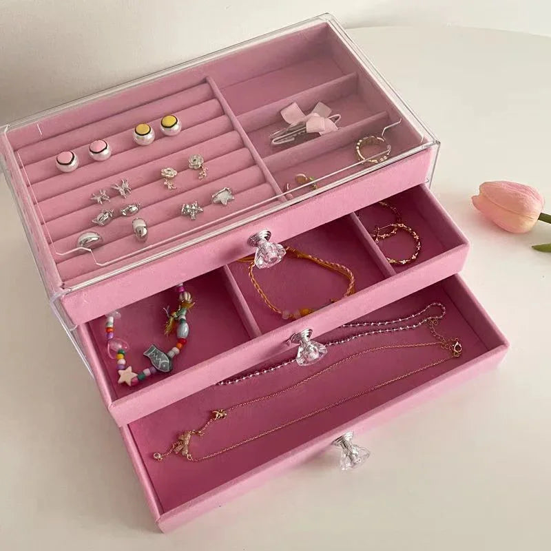 A clear acrylic jewelry organizer featuring multiple compartments and drawers, designed to neatly store and display rings, necklaces, bracelets, and earrings. Its transparent design allows for easy visibility of contents, while the compact structure fits seamlessly on a vanity or dresser, keeping accessories organized and easily accessible