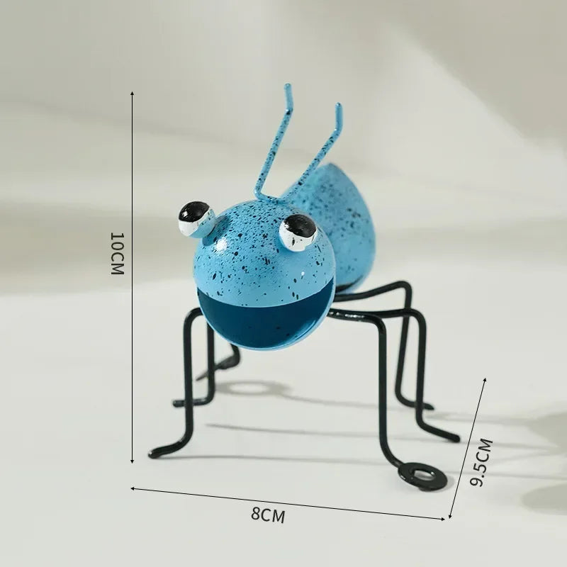 A whimsical metal ant sculpture designed as a garden ornament. The ant features a rustic finish, detailed body segments, and expressive antennae, adding a touch of charm and playfulness to outdoor spaces