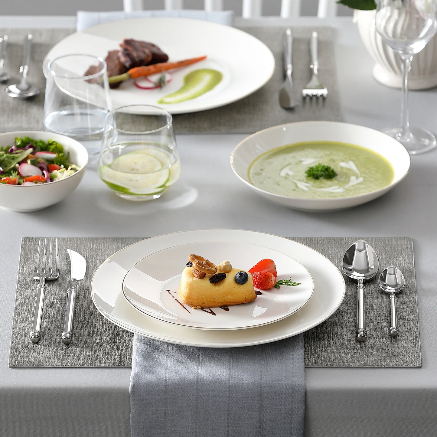 A complete dinnerware set including dinner plates, salad plates, bowls, and mugs, all featuring a sleek, modern design in a neutral color palette