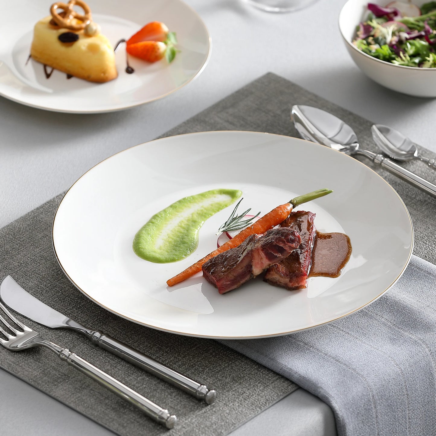 A complete dinnerware set including dinner plates, salad plates, bowls, and mugs, all featuring a sleek, modern design in a neutral color palette