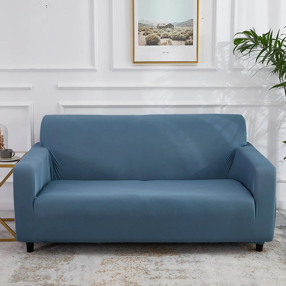 A tailored cover designed to fit an L-shaped sectional sofa, crafted from stretchable, durable fabric in a neutral tone. The cover snugly fits over the sofa, providing protection against spills, stains, and wear, while seamlessly blending with modern living room decor.