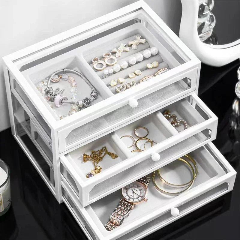 A clear acrylic jewelry organizer featuring multiple compartments and drawers, designed to neatly store and display rings, necklaces, bracelets, and earrings. Its transparent design allows for easy visibility of contents, while the compact structure fits seamlessly on a vanity or dresser, keeping accessories organized and easily accessible