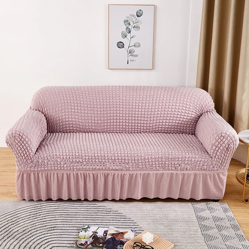 Stretchable sofa cover in a neutral tone, fitting snugly over a three-seater couch, providing protection and a refreshed look to the living room furniture
