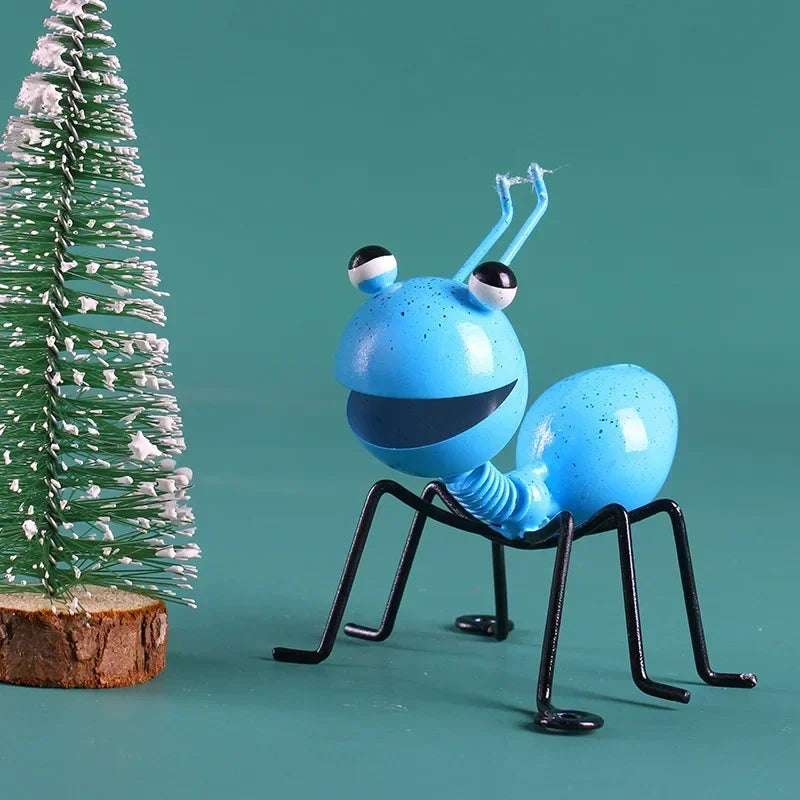 A whimsical metal ant sculpture designed as a garden ornament. The ant features a rustic finish, detailed body segments, and expressive antennae, adding a touch of charm and playfulness to outdoor spaces