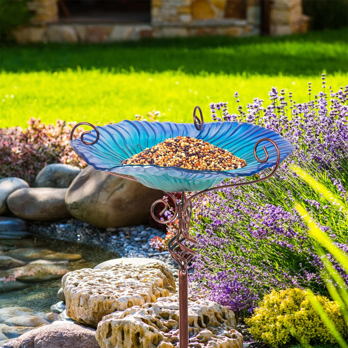 A decorative garden birdbath featuring a glass bowl with a flower design, mounted on a tall pedestal. The vibrant colors and intricate patterns attract birds while adding a touch of elegance to outdoor spaces.