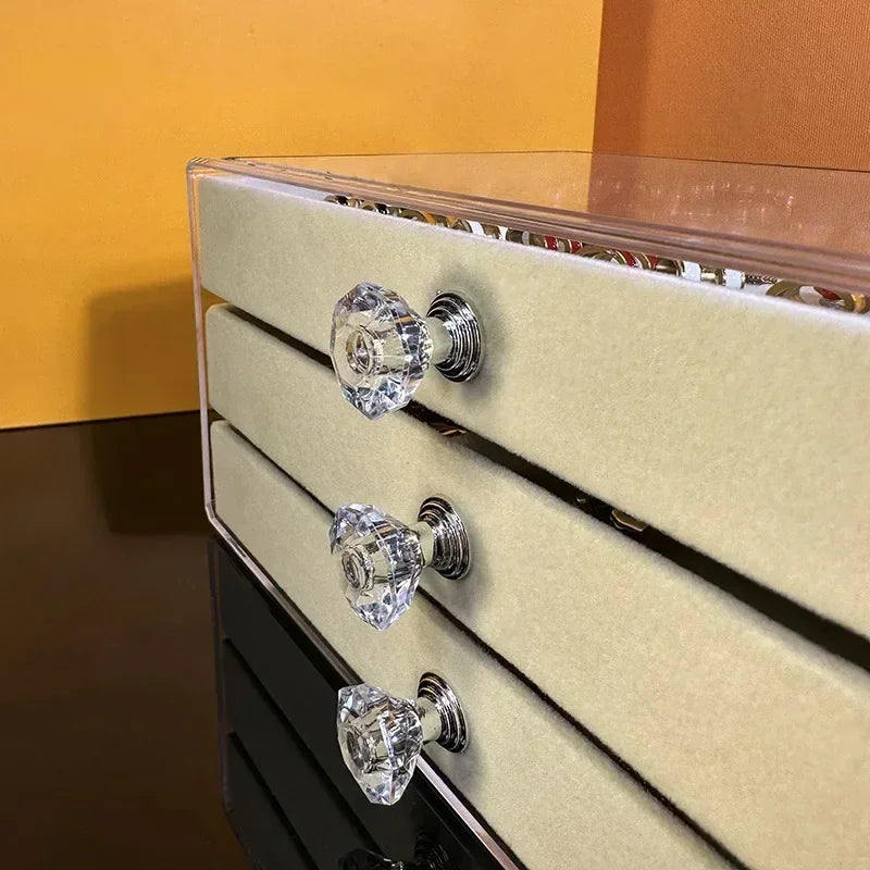 A clear acrylic jewelry organizer featuring multiple compartments and drawers, designed to neatly store and display rings, necklaces, bracelets, and earrings. Its transparent design allows for easy visibility of contents, while the compact structure fits seamlessly on a vanity or dresser, keeping accessories organized and easily accessible