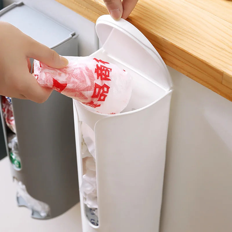 A wall-mounted plastic bag holder made of durable stainless steel with a sleek silver finish. Designed to neatly store and dispense plastic grocery bags, it features a top opening for easy insertion and a front slot for convenient retrieval, helping to keep your kitchen organized and clutter-free.