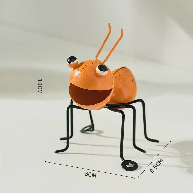 A whimsical metal ant sculpture designed as a garden ornament. The ant features a rustic finish, detailed body segments, and expressive antennae, adding a touch of charm and playfulness to outdoor spaces