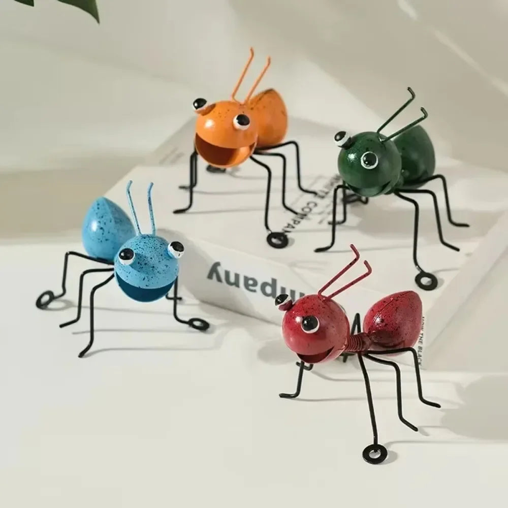 A whimsical metal ant sculpture designed as a garden ornament. The ant features a rustic finish, detailed body segments, and expressive antennae, adding a touch of charm and playfulness to outdoor spaces