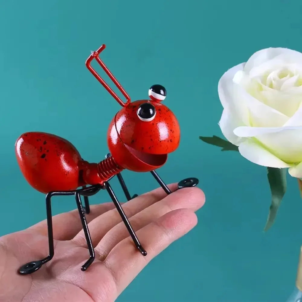 A whimsical metal ant sculpture designed as a garden ornament. The ant features a rustic finish, detailed body segments, and expressive antennae, adding a touch of charm and playfulness to outdoor spaces