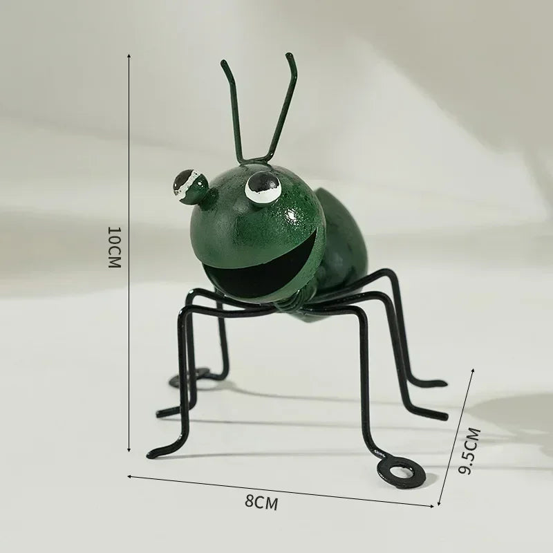 A whimsical metal ant sculpture designed as a garden ornament. The ant features a rustic finish, detailed body segments, and expressive antennae, adding a touch of charm and playfulness to outdoor spaces