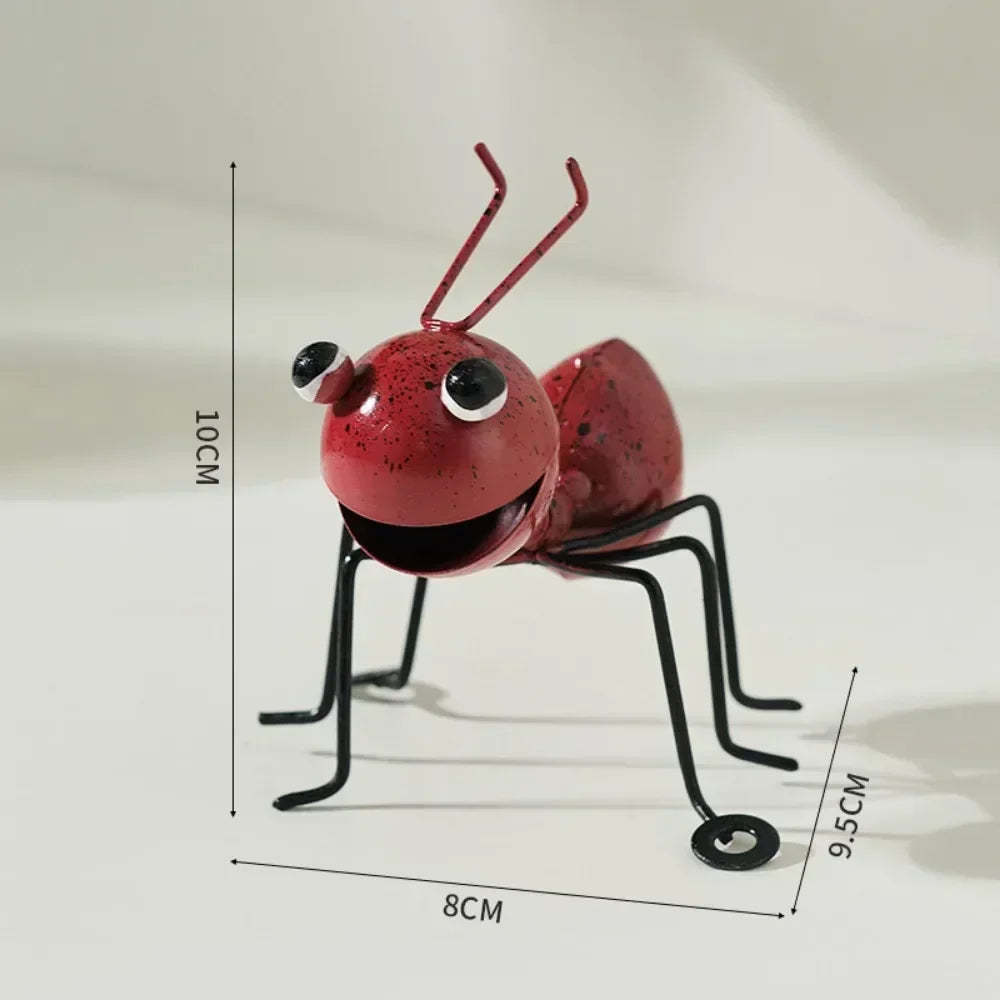 A whimsical metal ant sculpture designed as a garden ornament. The ant features a rustic finish, detailed body segments, and expressive antennae, adding a touch of charm and playfulness to outdoor spaces