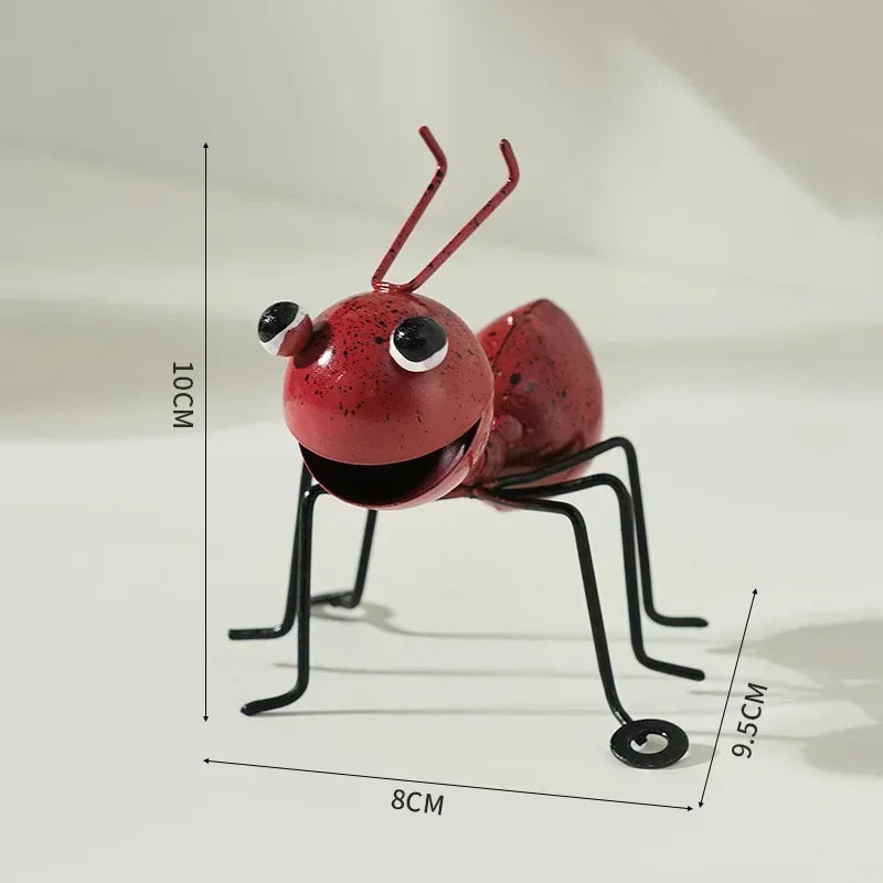 A whimsical metal ant sculpture designed as a garden ornament. The ant features a rustic finish, detailed body segments, and expressive antennae, adding a touch of charm and playfulness to outdoor spaces