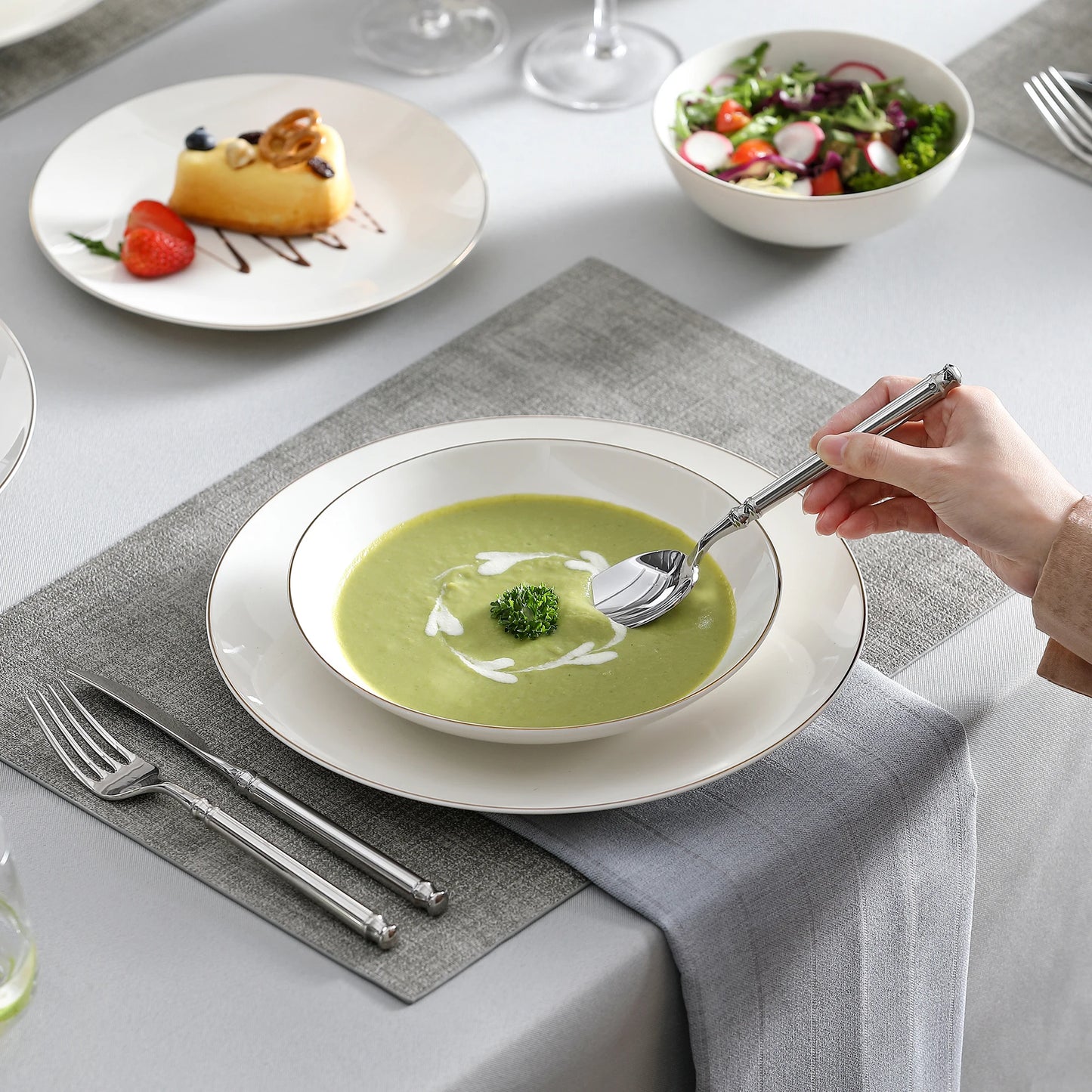 A complete dinnerware set including dinner plates, salad plates, bowls, and mugs, all featuring a sleek, modern design in a neutral color palette