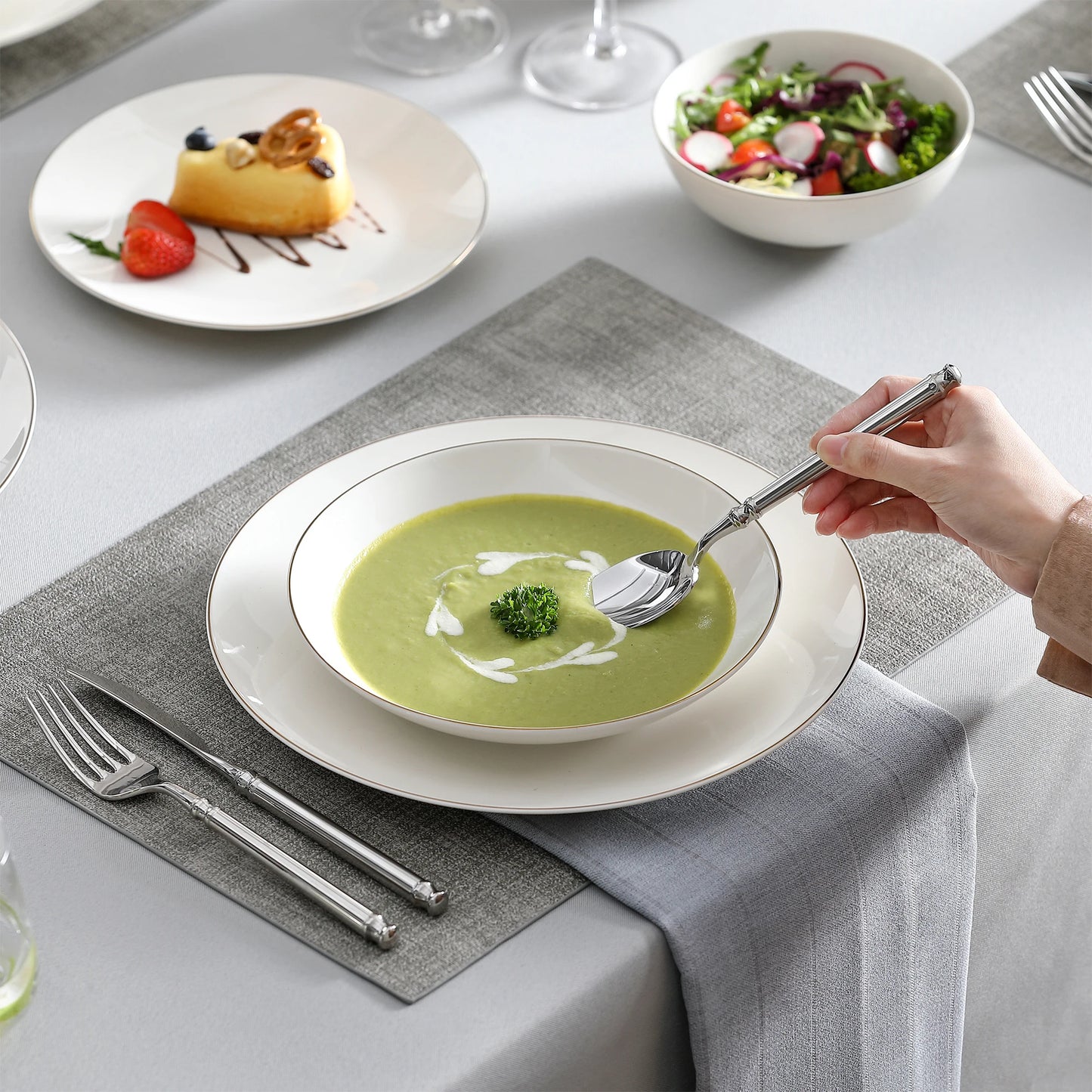A complete dinnerware set including dinner plates, salad plates, bowls, and mugs, all featuring a sleek, modern design in a neutral color palette