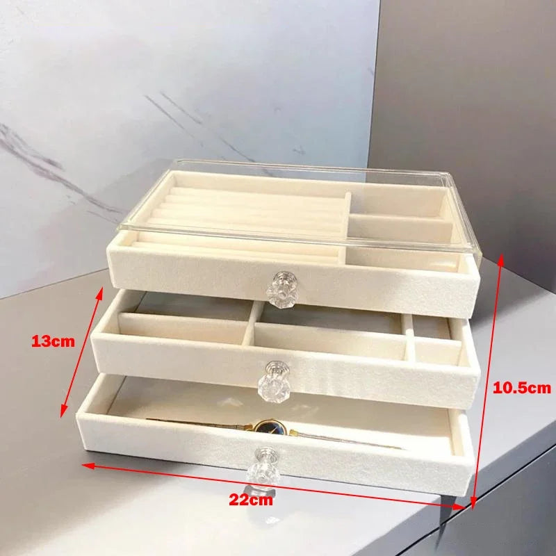 A clear acrylic jewelry organizer featuring multiple compartments and drawers, designed to neatly store and display rings, necklaces, bracelets, and earrings. Its transparent design allows for easy visibility of contents, while the compact structure fits seamlessly on a vanity or dresser, keeping accessories organized and easily accessible
