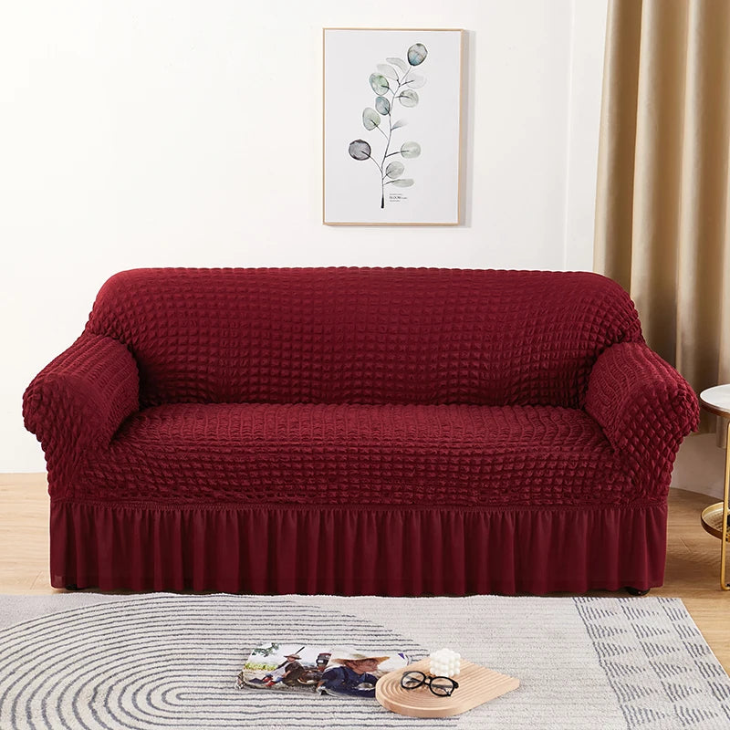 Stretchable sofa cover in a neutral tone, fitting snugly over a three-seater couch, providing protection and a refreshed look to the living room furniture