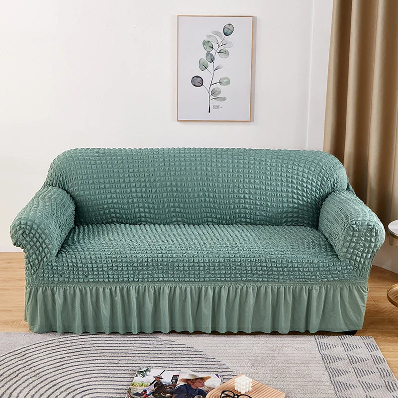 Stretchable sofa cover in a neutral tone, fitting snugly over a three-seater couch, providing protection and a refreshed look to the living room furniture