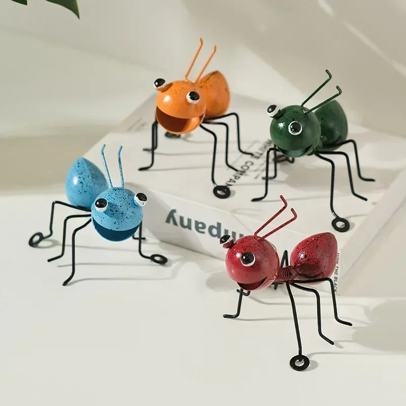 A whimsical metal ant sculpture designed as a garden ornament. The ant features a rustic finish, detailed body segments, and expressive antennae, adding a touch of charm and playfulness to outdoor spaces