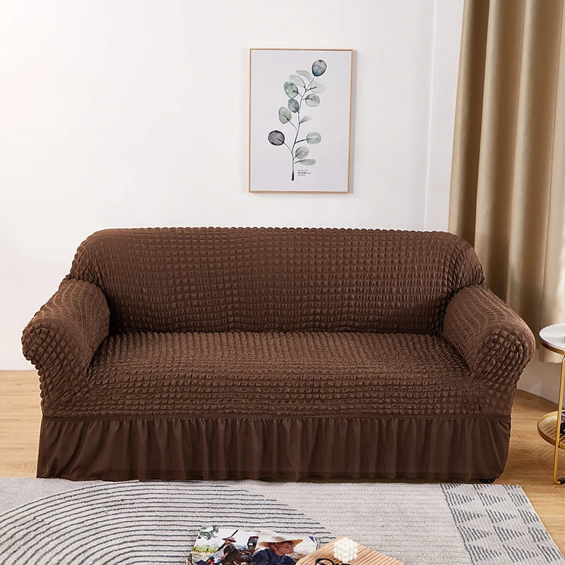 Stretchable sofa cover in a neutral tone, fitting snugly over a three-seater couch, providing protection and a refreshed look to the living room furniture