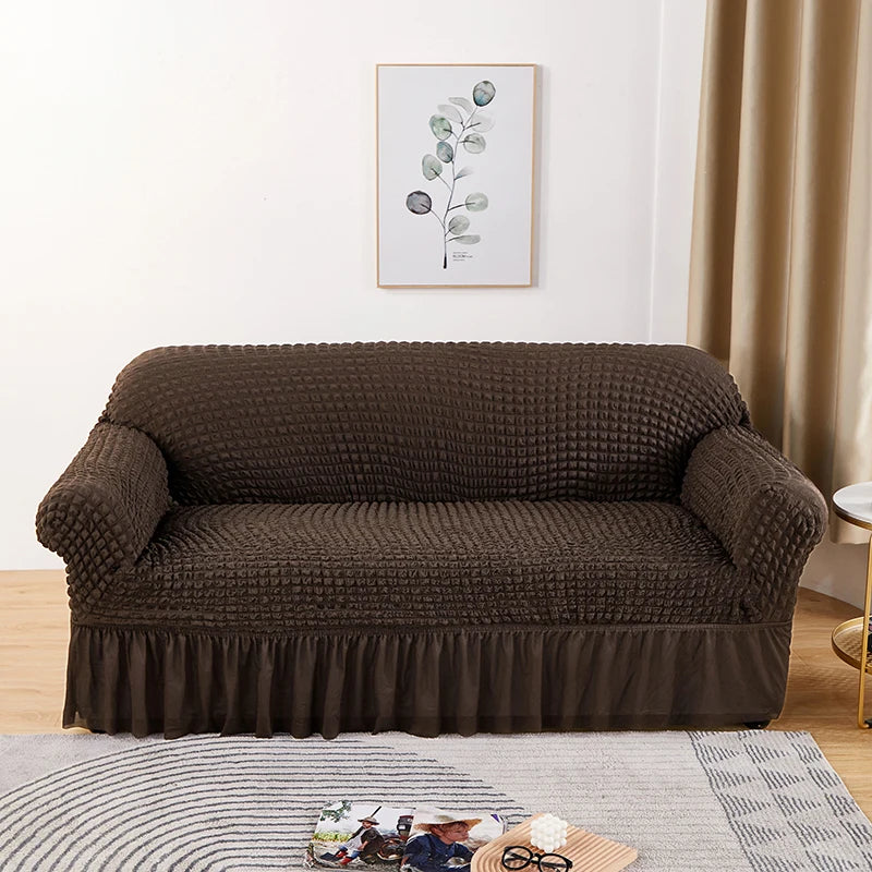 Stretchable sofa cover in a neutral tone, fitting snugly over a three-seater couch, providing protection and a refreshed look to the living room furniture