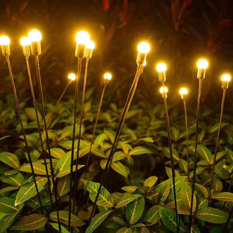 A collection of solar-powered garden lights illuminating a pathway at dusk. The lights, designed in various styles such as lanterns, stakes, and string lights, harness sunlight during the day and emit a warm, inviting glow in the evening, enhancing the ambiance of the outdoor space