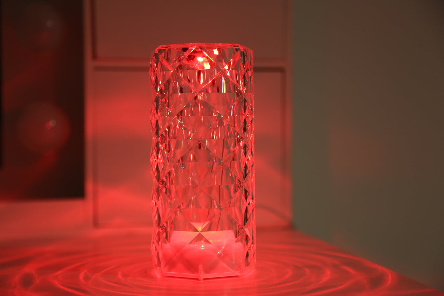 A crystal table lamp featuring a gleaming crystal base with intricate facets that refract light, complemented by an elegant lampshade. This decorative lighting piece adds a touch of sophistication and glamour to any room, creating a warm and inviting ambiance