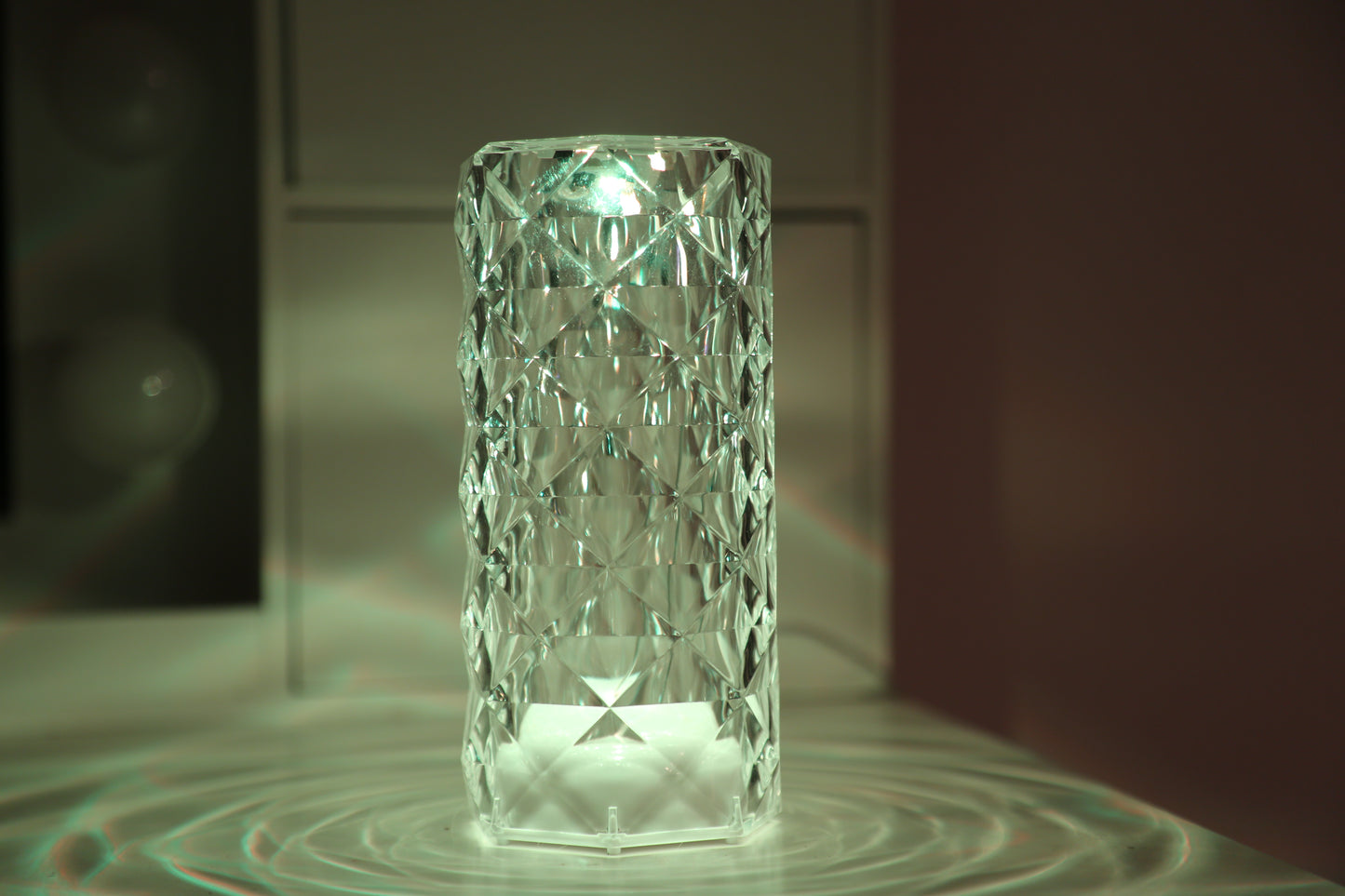 A crystal table lamp featuring a gleaming crystal base with intricate facets that refract light, complemented by an elegant lampshade. This decorative lighting piece adds a touch of sophistication and glamour to any room, creating a warm and inviting ambiance
