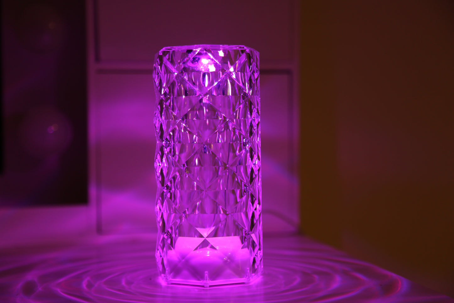A crystal table lamp featuring a gleaming crystal base with intricate facets that refract light, complemented by an elegant lampshade. This decorative lighting piece adds a touch of sophistication and glamour to any room, creating a warm and inviting ambiance