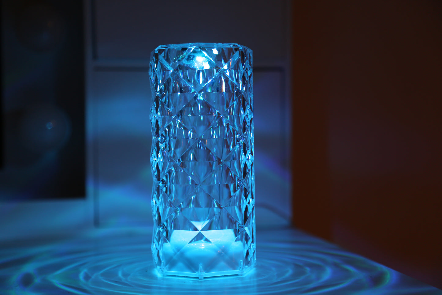 A crystal table lamp featuring a gleaming crystal base with intricate facets that refract light, complemented by an elegant lampshade. This decorative lighting piece adds a touch of sophistication and glamour to any room, creating a warm and inviting ambiance