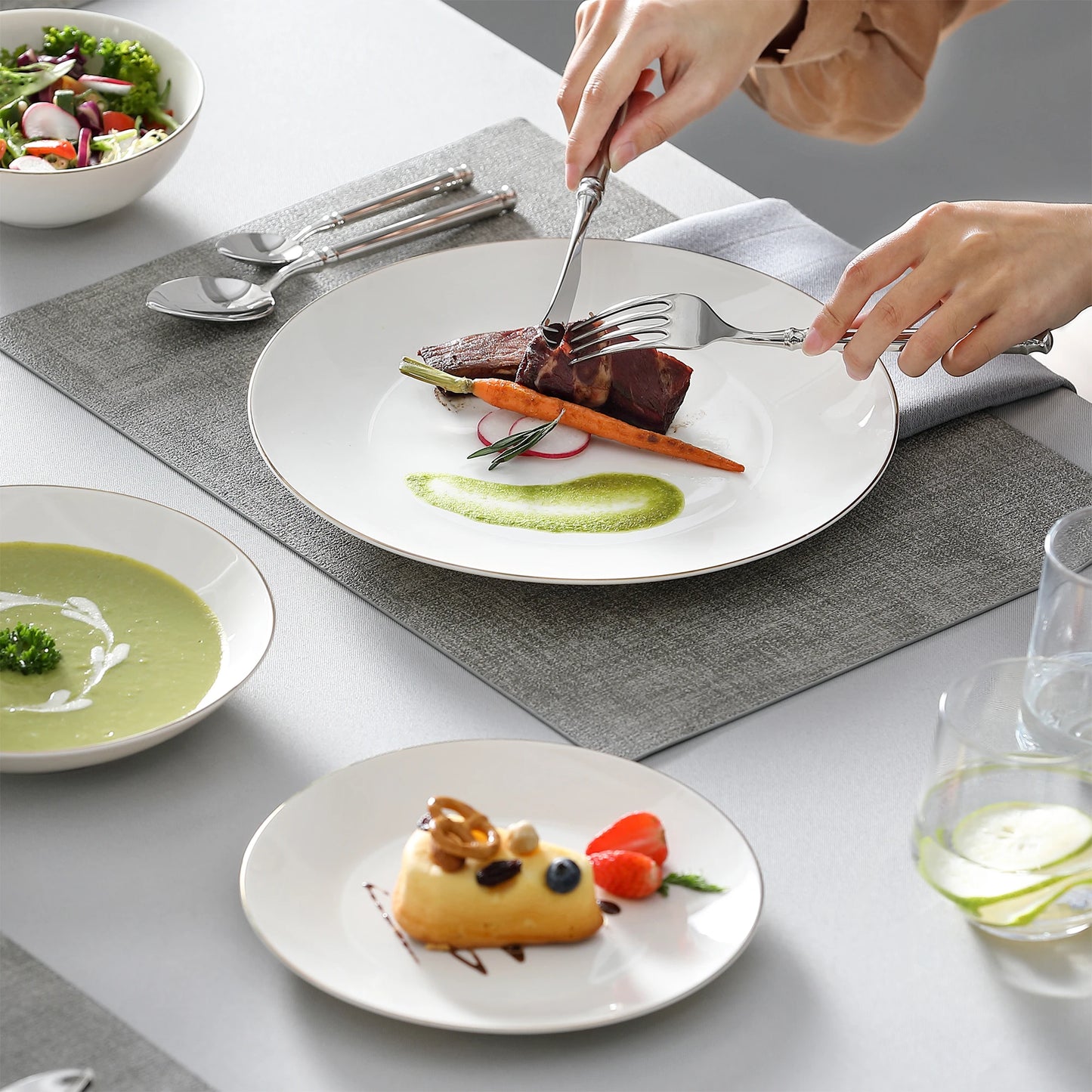 A complete dinnerware set including dinner plates, salad plates, bowls, and mugs, all featuring a sleek, modern design in a neutral color palette