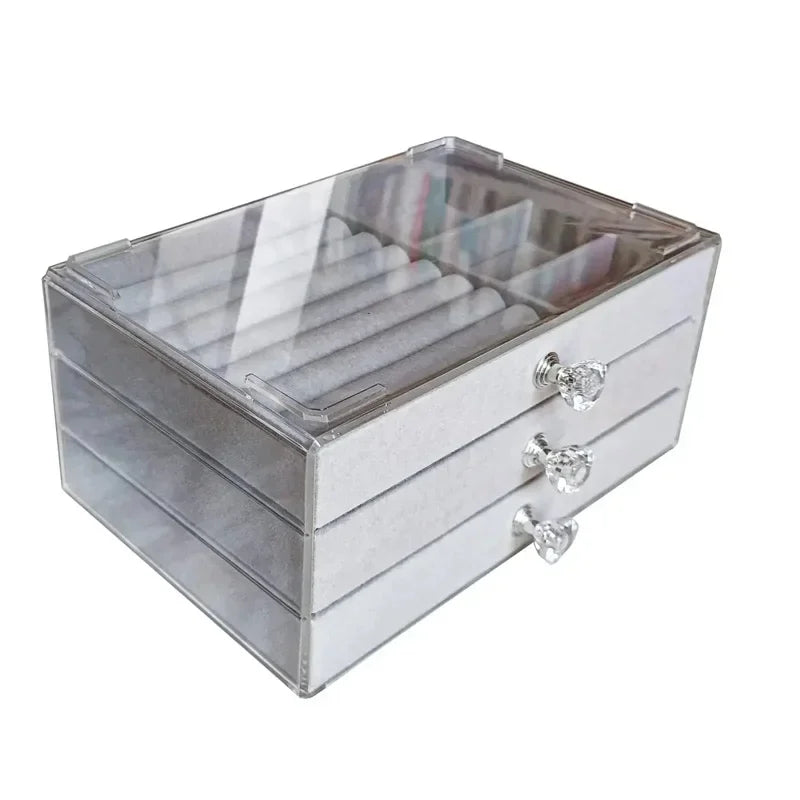 A clear acrylic jewelry organizer featuring multiple compartments and drawers, designed to neatly store and display rings, necklaces, bracelets, and earrings. Its transparent design allows for easy visibility of contents, while the compact structure fits seamlessly on a vanity or dresser, keeping accessories organized and easily accessible