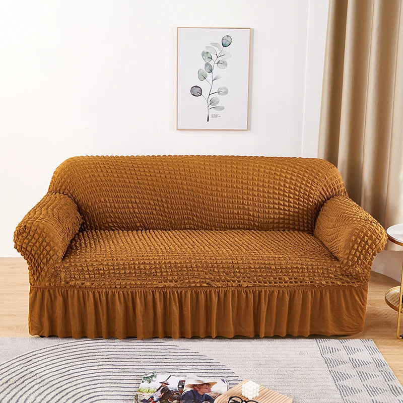Stretchable sofa cover in a neutral tone, fitting snugly over a three-seater couch, providing protection and a refreshed look to the living room furniture