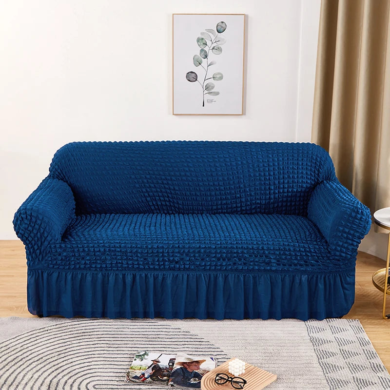 Stretchable sofa cover in a neutral tone, fitting snugly over a three-seater couch, providing protection and a refreshed look to the living room furniture