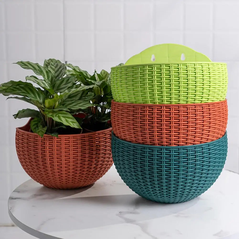 A durable plastic wall-mounted hanging planter in a half-round design, securely attached to a balcony railing. It is filled with vibrant blooming flowers, adding a touch of nature and color to the outdoor space.