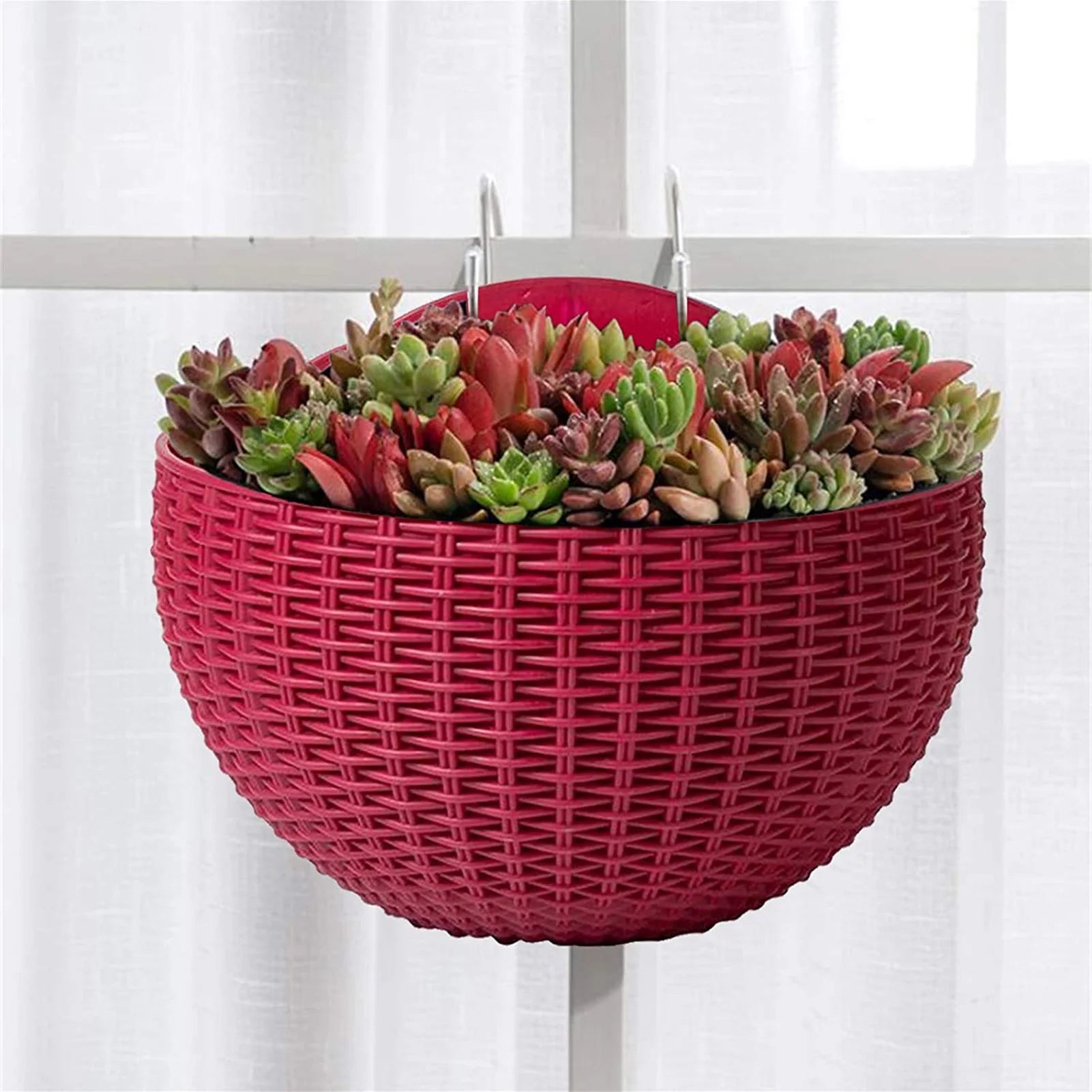 A durable plastic wall-mounted hanging planter in a half-round design, securely attached to a balcony railing. It is filled with vibrant blooming flowers, adding a touch of nature and color to the outdoor space.