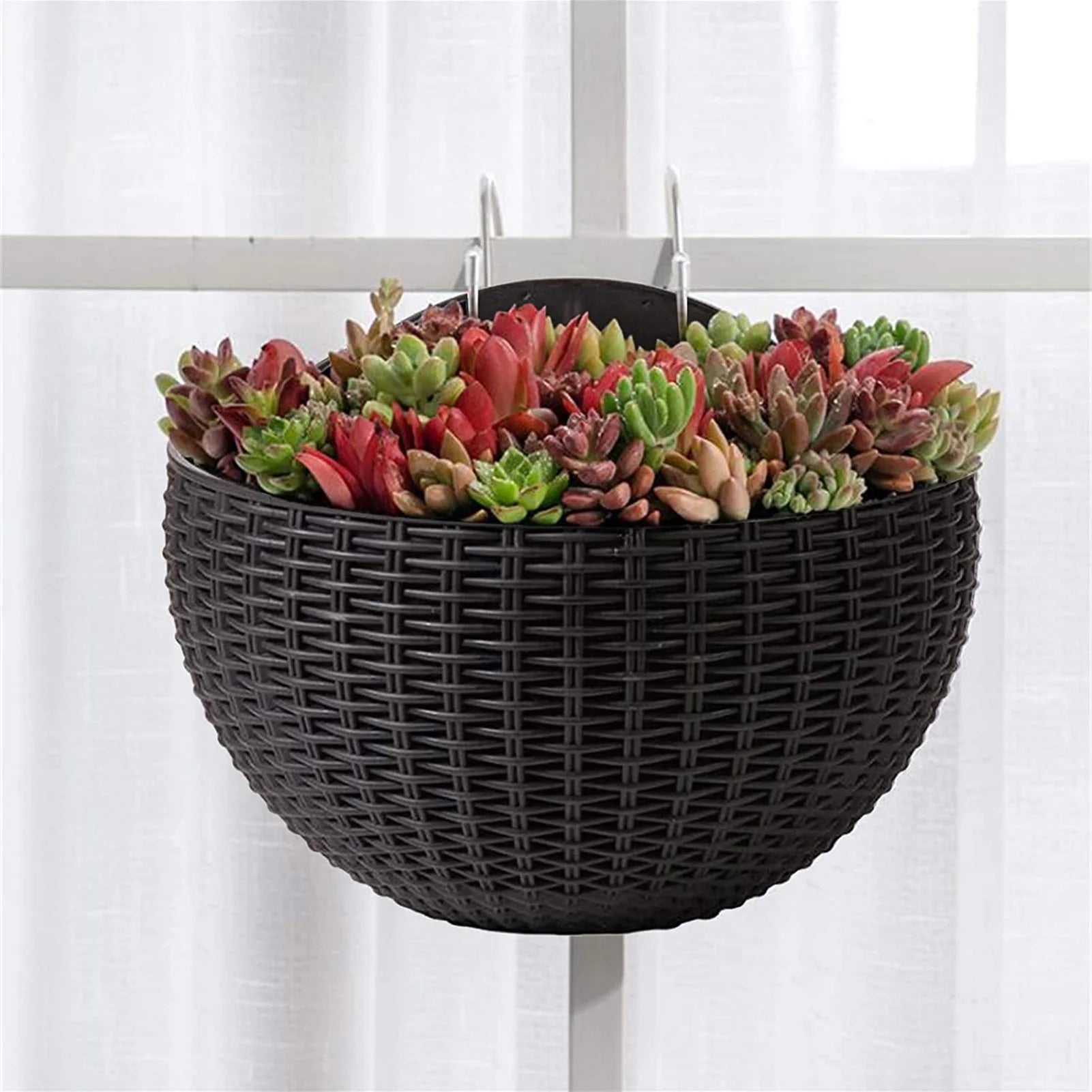 A durable plastic wall-mounted hanging planter in a half-round design, securely attached to a balcony railing. It is filled with vibrant blooming flowers, adding a touch of nature and color to the outdoor space.