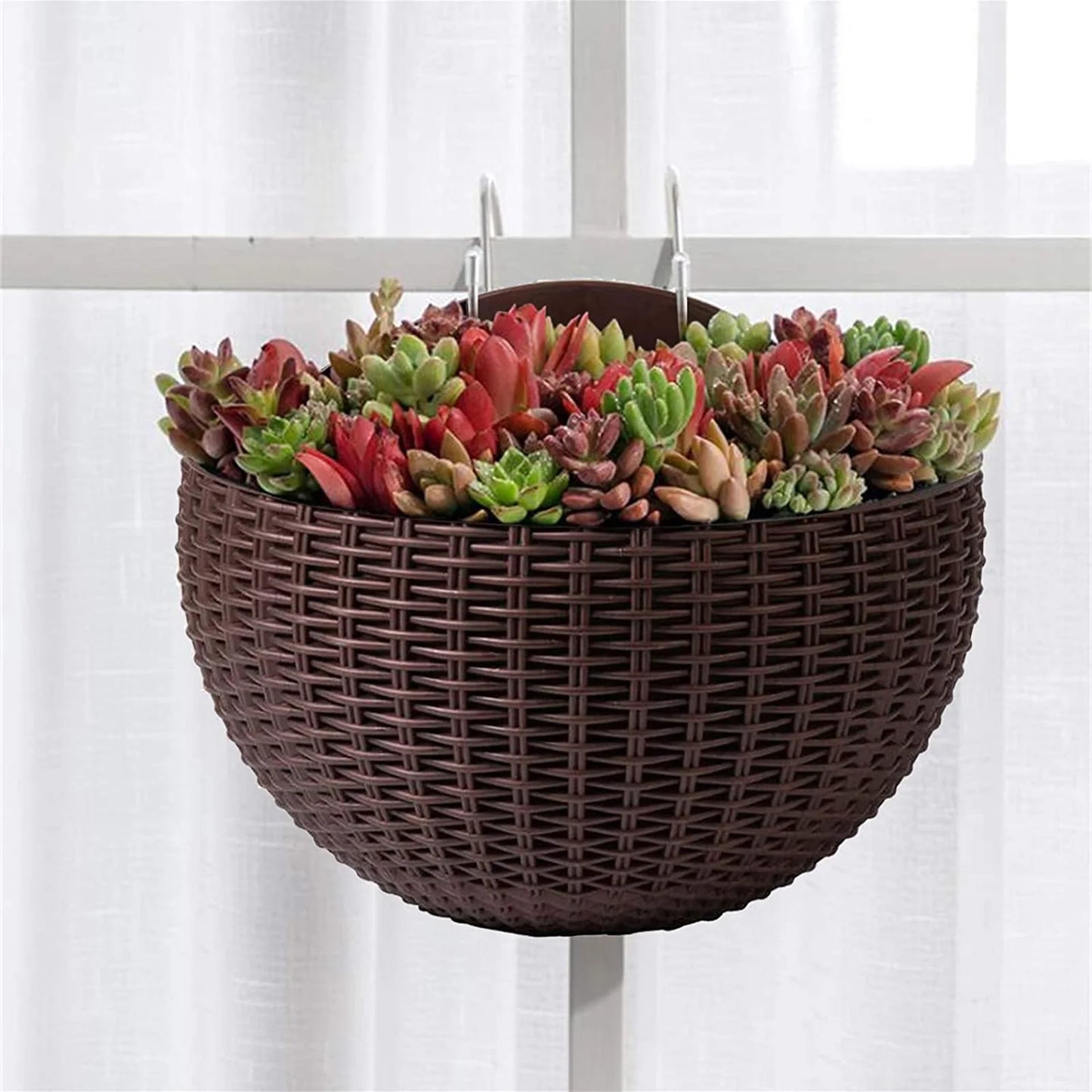 A durable plastic wall-mounted hanging planter in a half-round design, securely attached to a balcony railing. It is filled with vibrant blooming flowers, adding a touch of nature and color to the outdoor space.