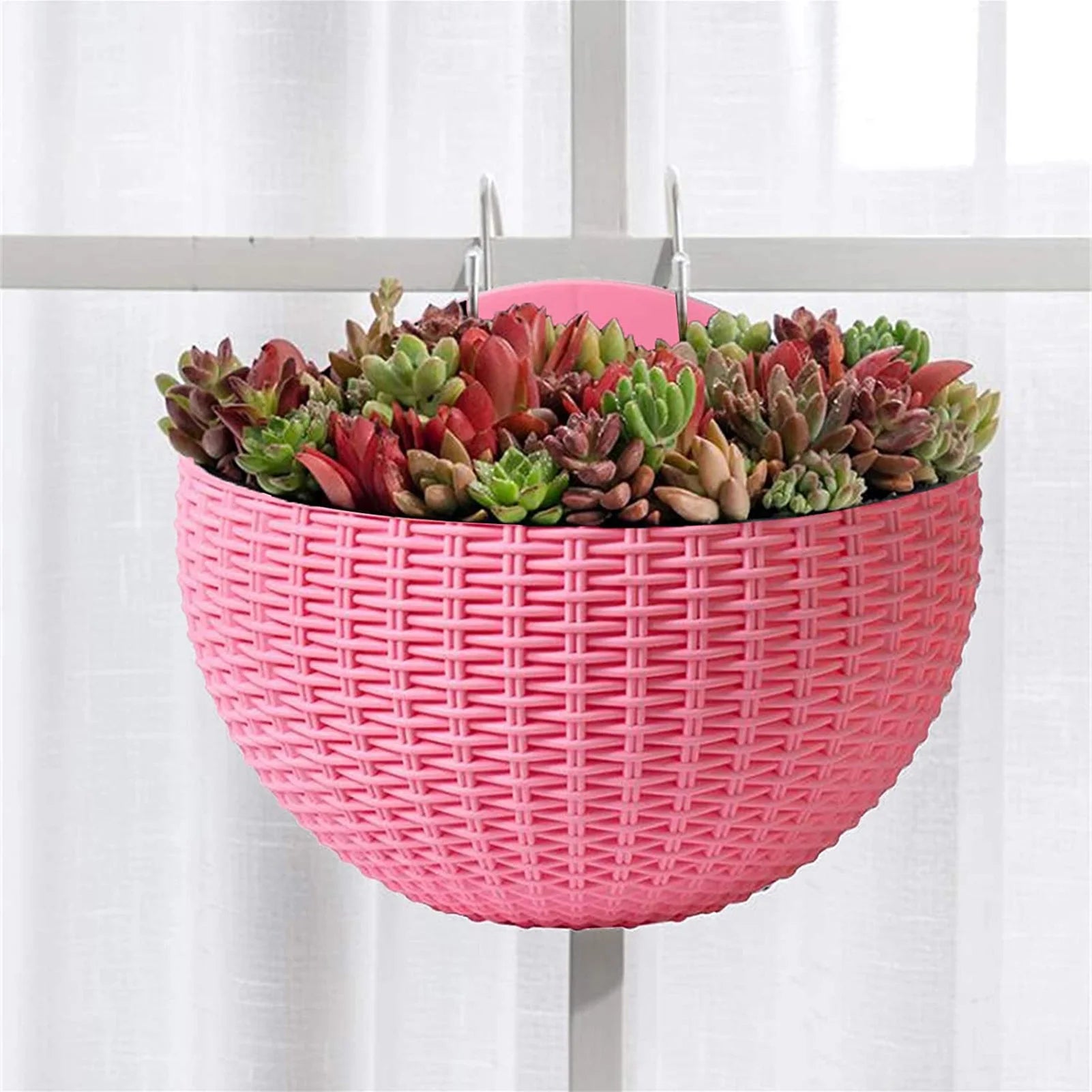 A durable plastic wall-mounted hanging planter in a half-round design, securely attached to a balcony railing. It is filled with vibrant blooming flowers, adding a touch of nature and color to the outdoor space.