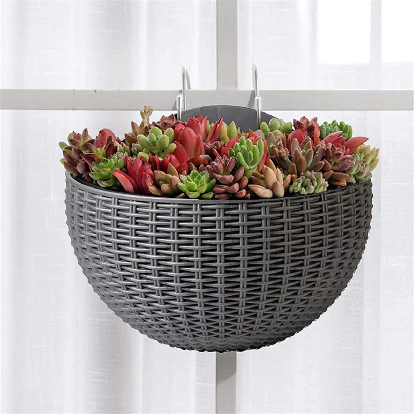 A durable plastic wall-mounted hanging planter in a half-round design, securely attached to a balcony railing. It is filled with vibrant blooming flowers, adding a touch of nature and color to the outdoor space.