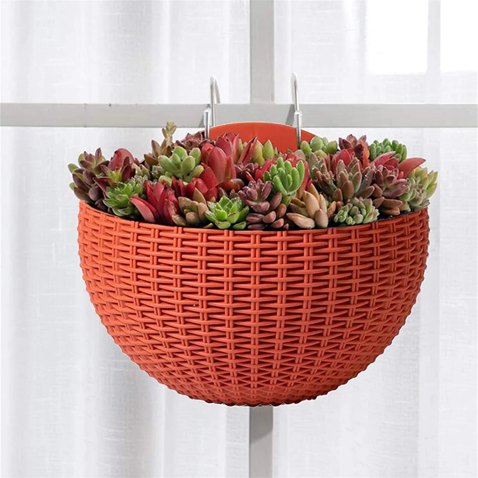 A durable plastic wall-mounted hanging planter in a half-round design, securely attached to a balcony railing. It is filled with vibrant blooming flowers, adding a touch of nature and color to the outdoor space.