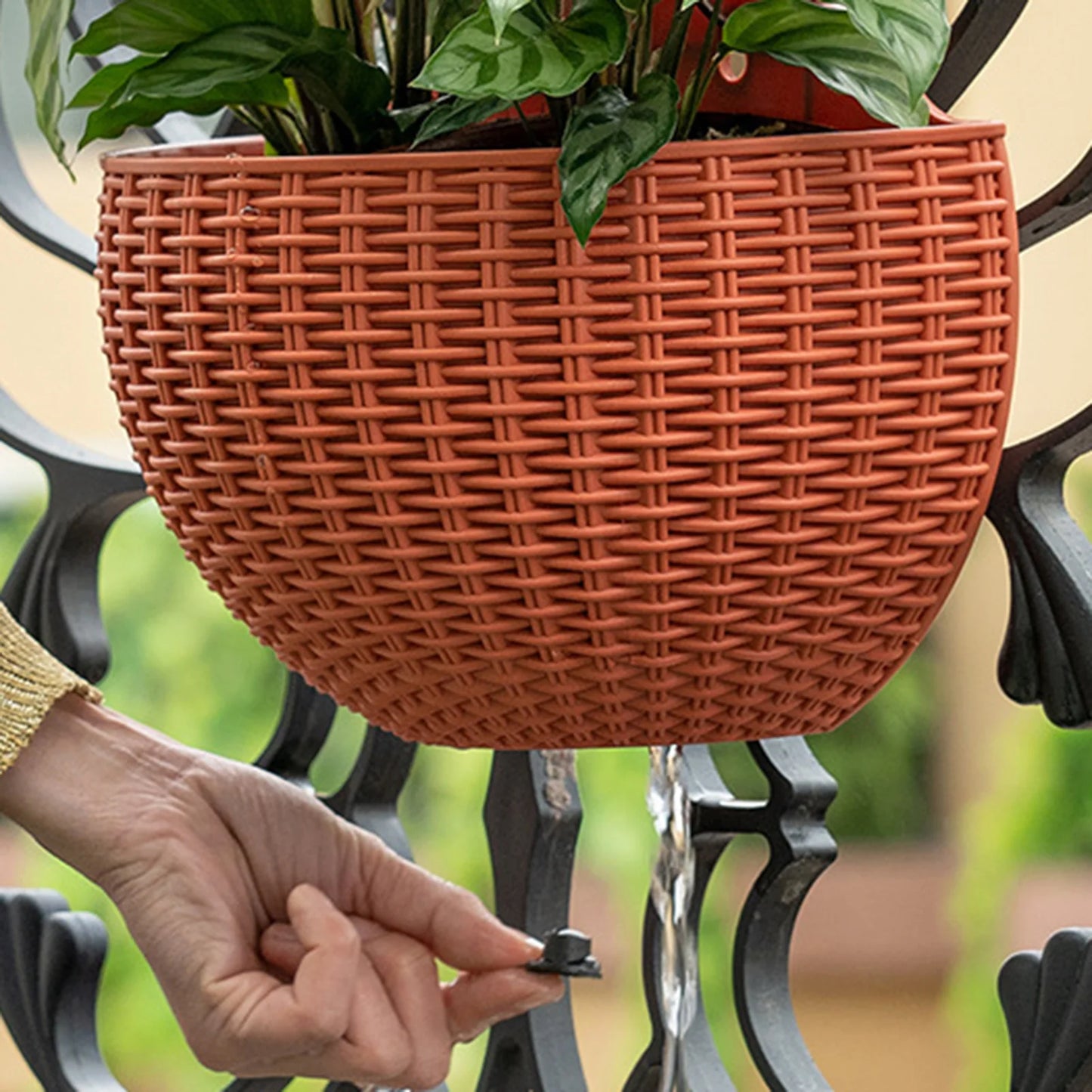 A durable plastic wall-mounted hanging planter in a half-round design, securely attached to a balcony railing. It is filled with vibrant blooming flowers, adding a touch of nature and color to the outdoor space.