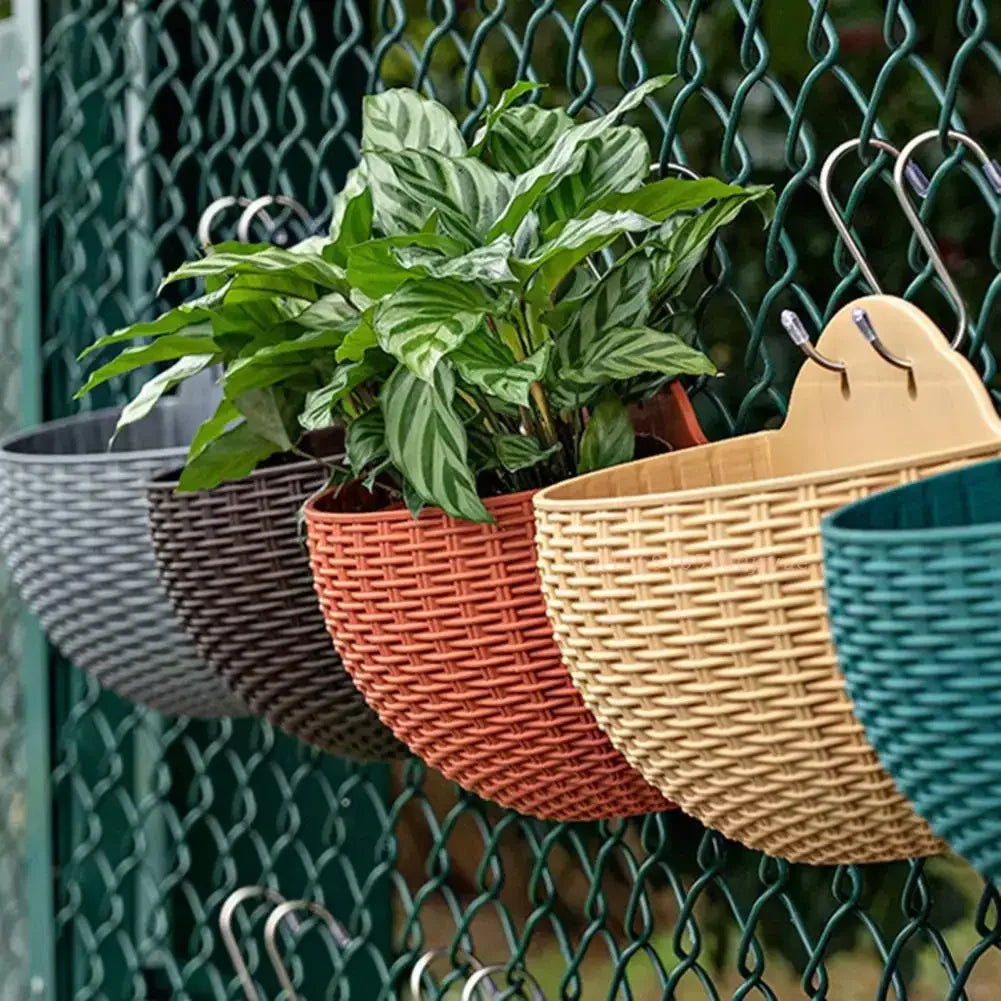 A durable plastic wall-mounted hanging planter in a half-round design, securely attached to a balcony railing. It is filled with vibrant blooming flowers, adding a touch of nature and color to the outdoor space.